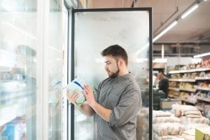 Man chooses frozen food in a supermarket fridge.