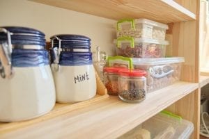 Wooden shelves with food and kitchen utensils in the pantry.