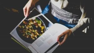 A person holding open a cookbook.